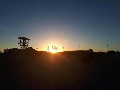 a sunset on a hill with the sun setting at Suíte Barros in Navegantes