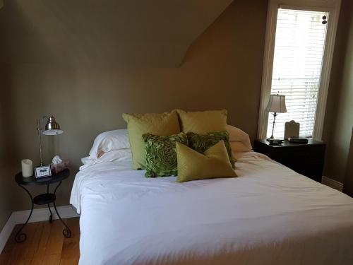 a bedroom with a large white bed with green pillows at Hellemsfield Inn & bed and breakfast in Kingsville