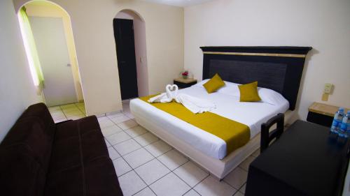 a bedroom with a large bed with yellow and white sheets at Hotel Tepic in Tepic