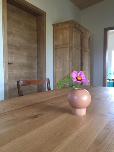 a pink flower in a vase on a wooden table at Au Chant du Vent in Tramelan