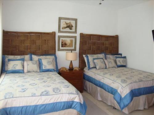 two beds in a bedroom with blue and white at Cap Cana Luxurious Marina Condo in Punta Cana