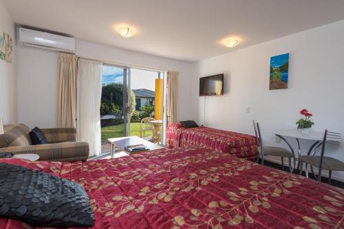 Habitación de hotel con cama y sala de estar. en Greens Motel en Nelson