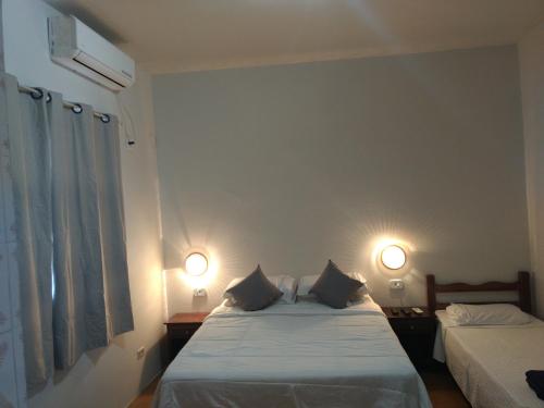 a bedroom with two beds and two lights on the wall at Hotel Pintado Azul in Coxim