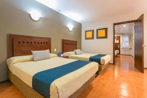 una camera d'albergo con due letti e un corridoio di Hotel Panamerican a Puebla