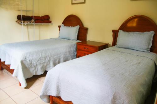 a bedroom with two beds with white sheets and a dresser at Apart Hotel Acuarious de Luis in Estelí