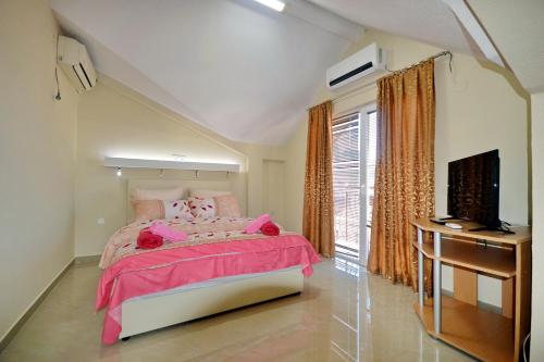 a bedroom with a pink bed and a television at Vila Tea Petrusevski in Ohrid