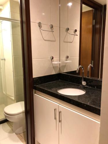 a bathroom with a sink and a toilet and a mirror at Apartamento na Praia de João Pessoa in João Pessoa