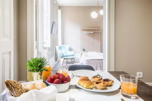a table with plates of bread and fruit on it at Gil Vicente - Charming Guesthouse in Porto