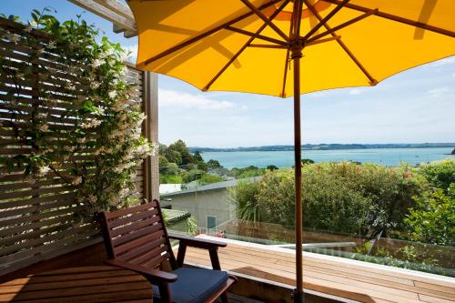 a yellow umbrella sitting on a porch with a view of the water at Te Manaaki Villa in Russell