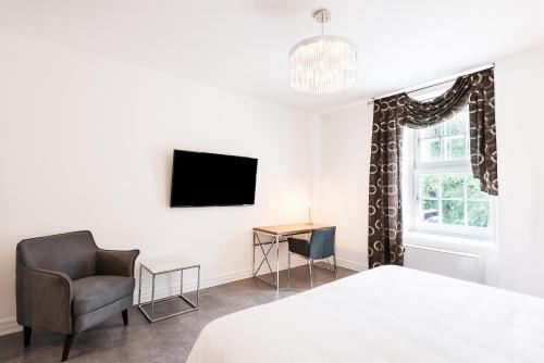 um quarto com uma cama, uma cadeira e uma televisão em Hotel Manoir Morgan em Cidade de Quebec