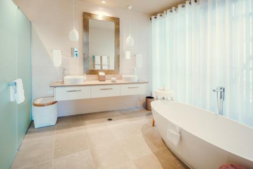 a bathroom with a tub and a sink and a mirror at Kinloch Manor & Villas in Kinloch
