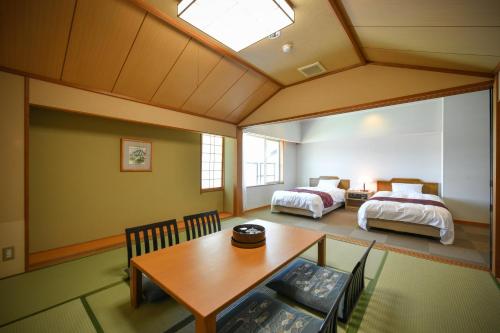 a bedroom with two beds and a table and a dining room at Awara Kitagata Onsen Kohanso Hana Yurari in Awara
