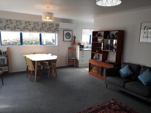 a living room with a table and a couch at Our Raglan Town House in Raglan
