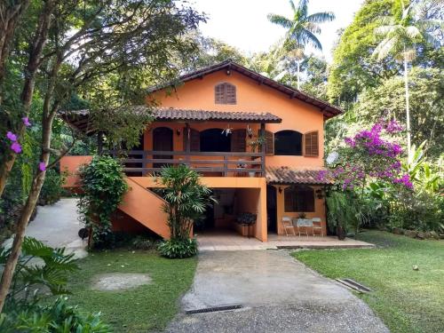 an orange house with a balcony and trees at Casa em penedo com cachoeira in Penedo