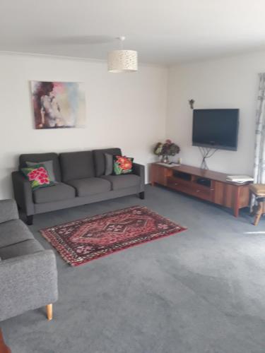 a living room with a couch and a flat screen tv at Our Raglan Town House in Raglan