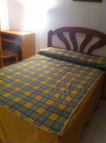 Los AmarguillosにあるApartamento Playa de Veraの青と黄色のチェック毛布が付いたベッド