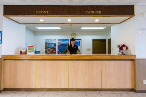 a man standing at the front counter of a cashier at Tsushima Dae-A Hotel in Tsushima