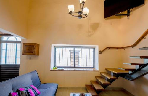 a living room with a blue couch and stairs at AC Loft studio gran ubicación en el centro in Querétaro