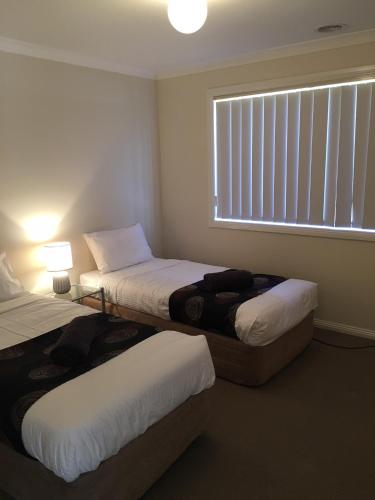 a bedroom with two beds and a window with blinds at Melton Apartments in Melton