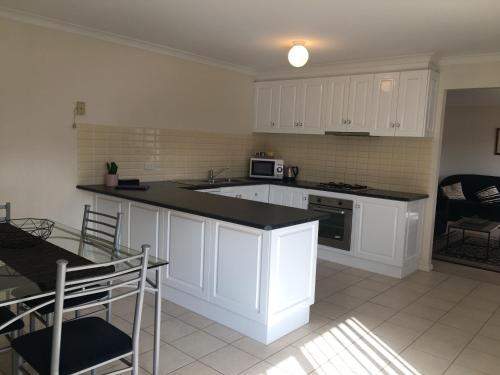 a kitchen with white cabinets and a black counter top at Melton Apartments in Melton