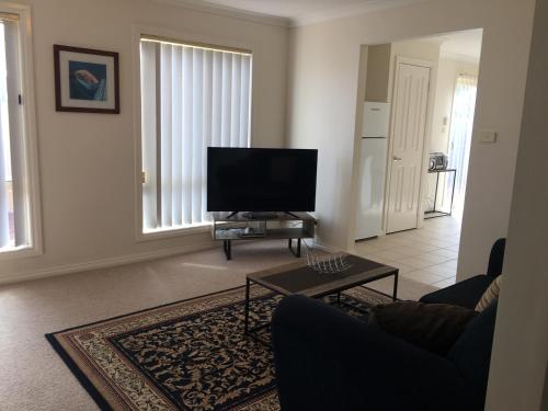 a living room with a tv and a couch and a table at Melton Apartments in Melton