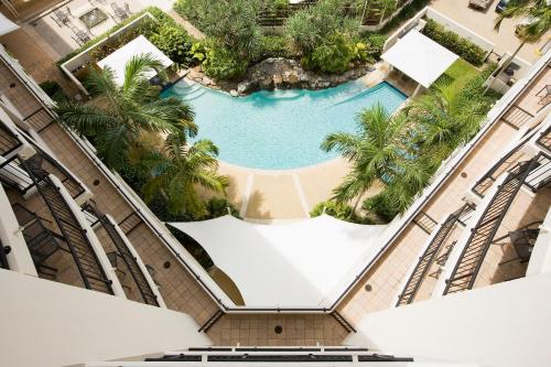 an overhead view of a pool in a building with palm trees at Mantra Esplanade in Cairns