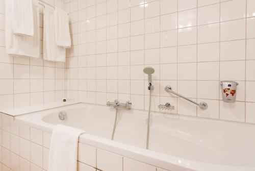 a white bath tub sitting next to a white sink at Best Western Museumhotels Delft in Delft