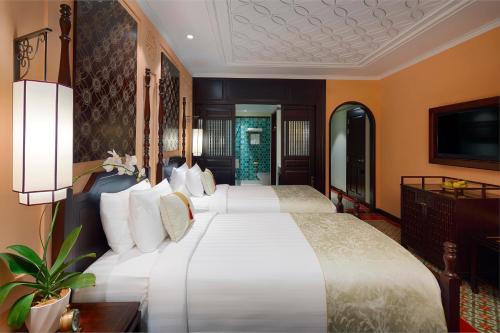 a hotel room with two beds and a television at Little Riverside Hoi An . A Luxury Hotel & Spa in Hoi An