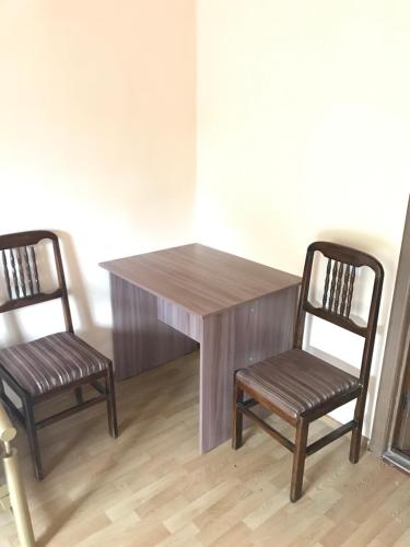 a wooden table and two chairs in a room at Гостиница Альянс in Karagandy