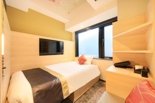 a small bedroom with a bed and a tv at The Hedistar Hotel Kyoto Nijo Comic & Books in Kyoto