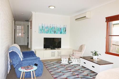 a living room with a blue chair and a tv at Jodi's Beach Retreat Eden in Eden