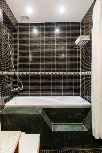 a bathroom with a bath tub in a black tiled at Nghi Son Hotel in Xóm Dữa