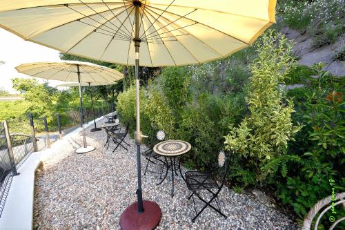 a patio with two tables and a yellow umbrella at Spagnoi Rooms in Castelnuovo del Garda