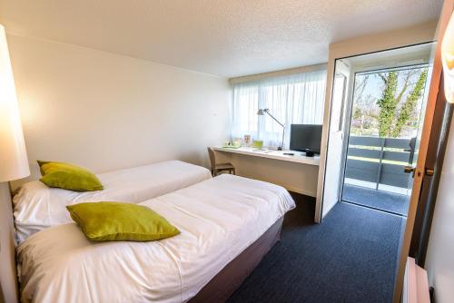 a hotel room with two beds and a desk and a window at Campanile Toulouse Sesquieres in Toulouse