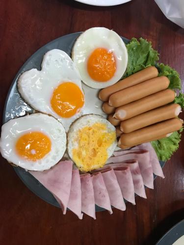 a plate of eggs sausage and hot dogs on a table at Khaokhab Lodge in Nong Nam Daeng