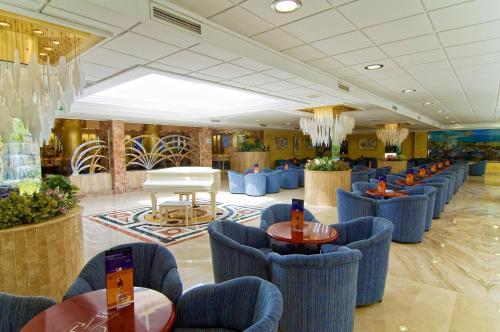 a lobby with blue chairs and tables in a building at Hotel Servigroup Diplomatic in Benidorm