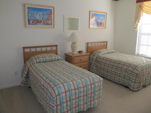 a bedroom with two beds and a table with a lamp at Wish Upon a Mouse in Kissimmee