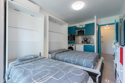 Dos camas en una habitación con paredes azules. en Beautiful studio near sea (free parking), en Roquebrune-Cap-Martin