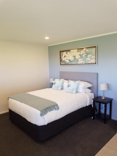 a bedroom with a large white bed with a painting on the wall at Murchison View Studio in Te Anau