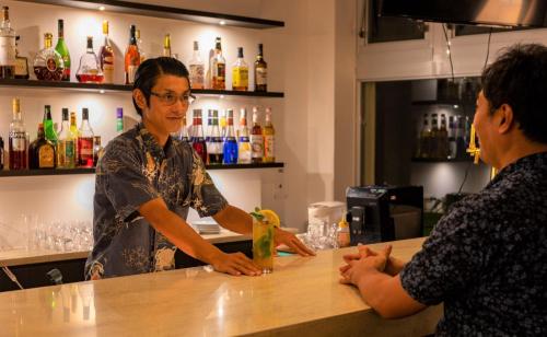 a woman standing at a bar talking to a bartender at EN RESORT Kumejima EEF Beach Hotel in Kumejima