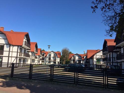 a row of houses with a fence and cars at Apartamenty Porto Eli in Rowy