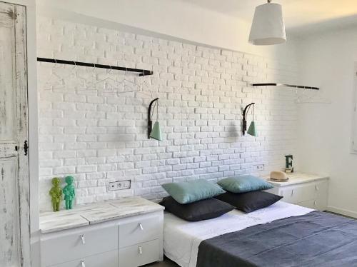 sypialnia z białą ceglaną ścianą i łóżkiem w obiekcie Le 40 w mieście LʼIsle-sur-la-Sorgue