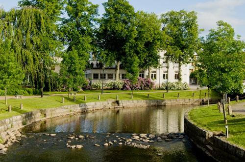 a river in a park with a building in the background at Amals Stadshotell, BW Signature Collection in Åmål