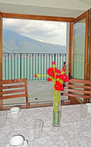 a vase with red flowers sitting on a table at Casa De Pol Exclusive Lake View by Gardadomusmea in Tremosine Sul Garda