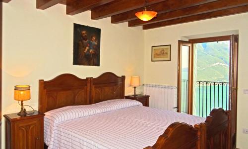 a bedroom with a wooden bed and a window at Casa De Pol Exclusive Lake View by Gardadomusmea in Tremosine Sul Garda
