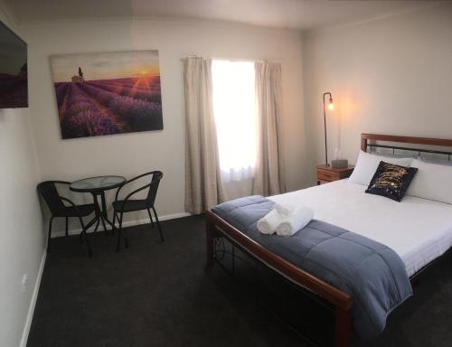 a bedroom with a bed and a table and a window at 3ree- Spacious & Charming Apartment in Devonport