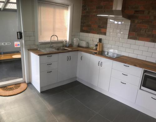 a kitchen with white cabinets and a sink at 3ree- Spacious & Charming Apartment in Devonport