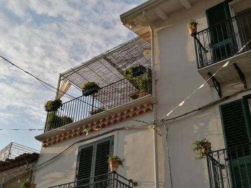 a white house with potted plants on the balconies at La Via del Carretto B&B in Capri Leone