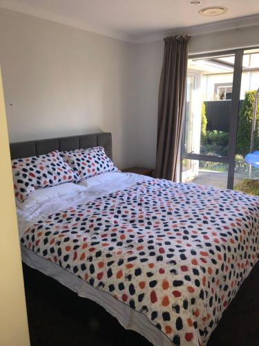 a bedroom with a bed with a colorful comforter at Memorial holiday home in Christchurch