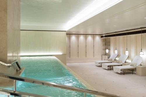 uma piscina num quarto de hotel com cadeiras e uma piscina em The Lanesborough, Oetker Collection em Londres